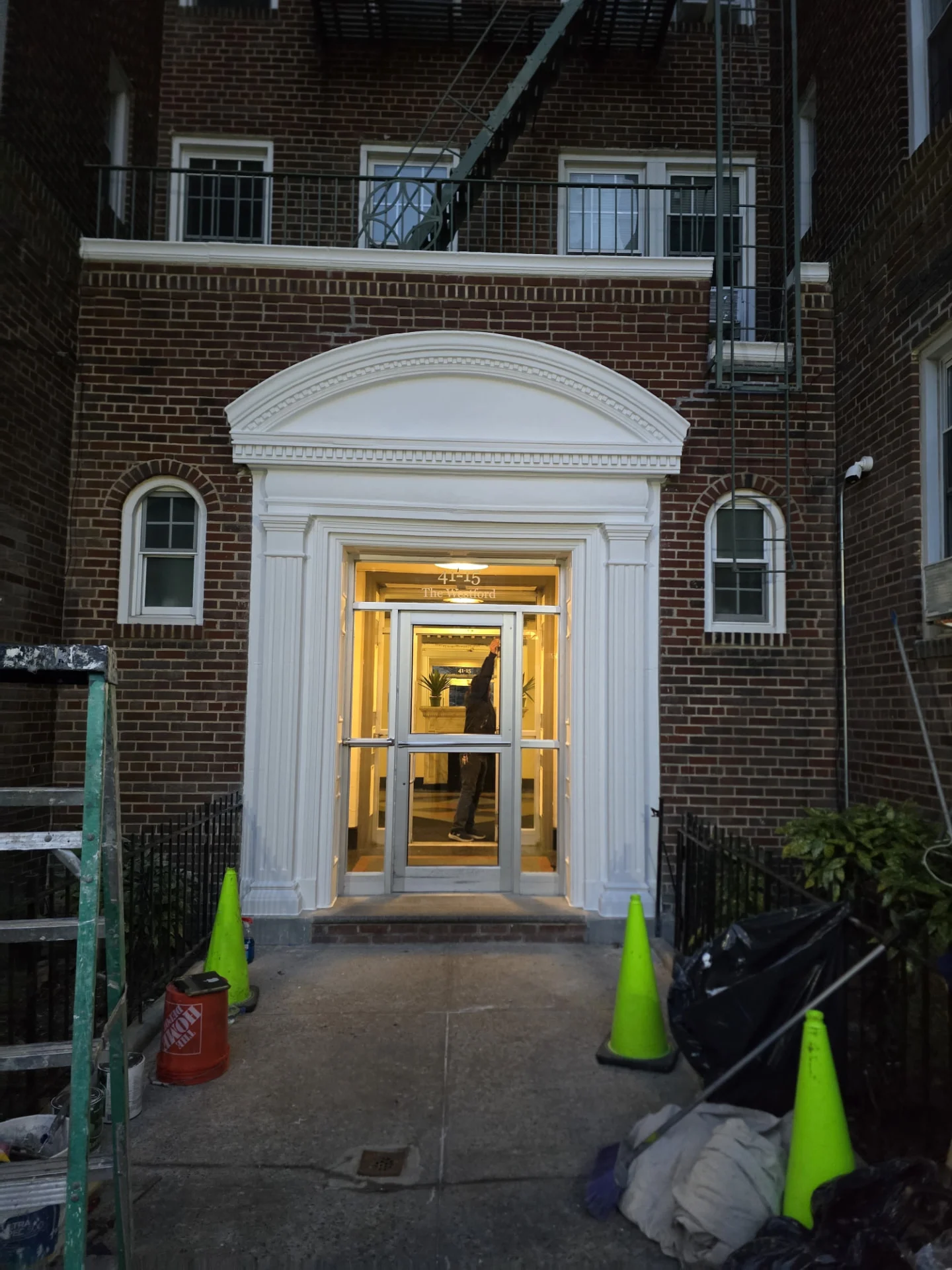 Building entrance after restoration: clean, repaired white architectural molding with fresh paint and illuminated entryway