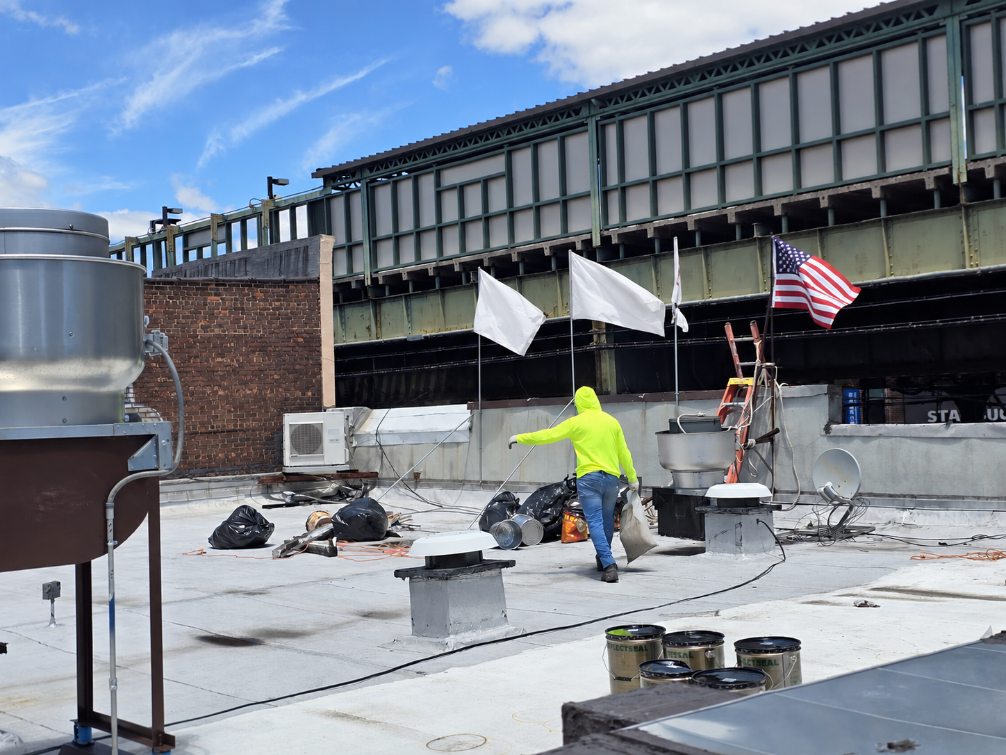North Star worker in a bright green shirt on a rooftop with white flags